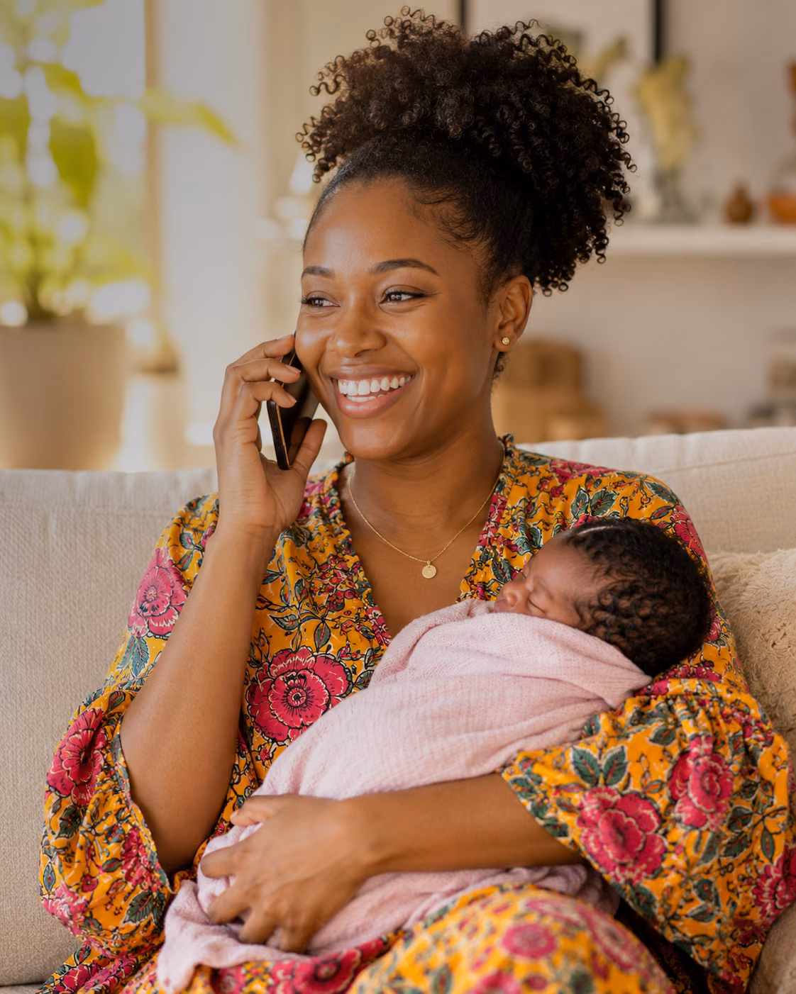 New mother holding her baby while speaking on the phone